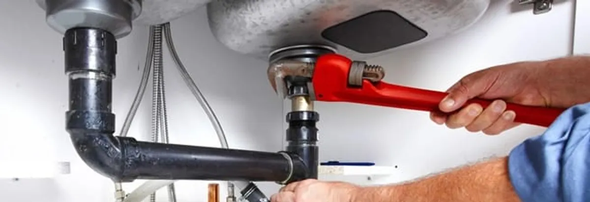 Garbage disposal repair technician tightening the sink drain and disposal connection in Evansville, IN