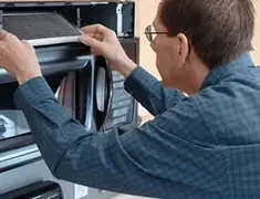 Appliance repair technician replacing a microwave vent filter in Evansville, IN