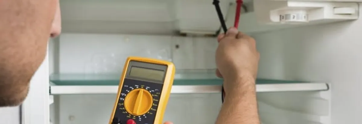 Refrigerator repair technician testing electrical components with a multimeter in Evansville, IN